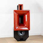 Red and black speaker on a white floor with a white wall background