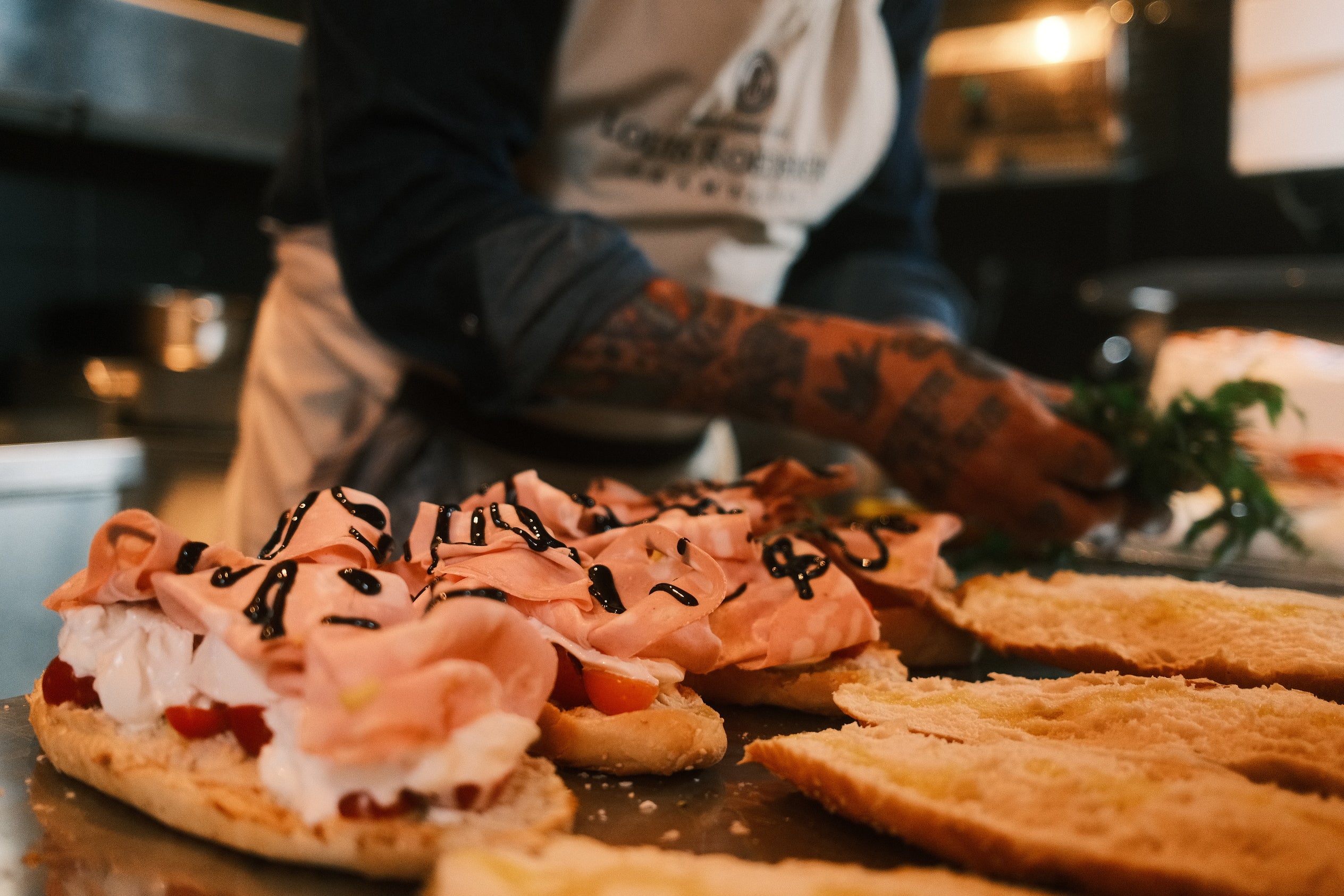 Person preparing food in a kitchen with a focus on a dish with pink toppings and bread slices.