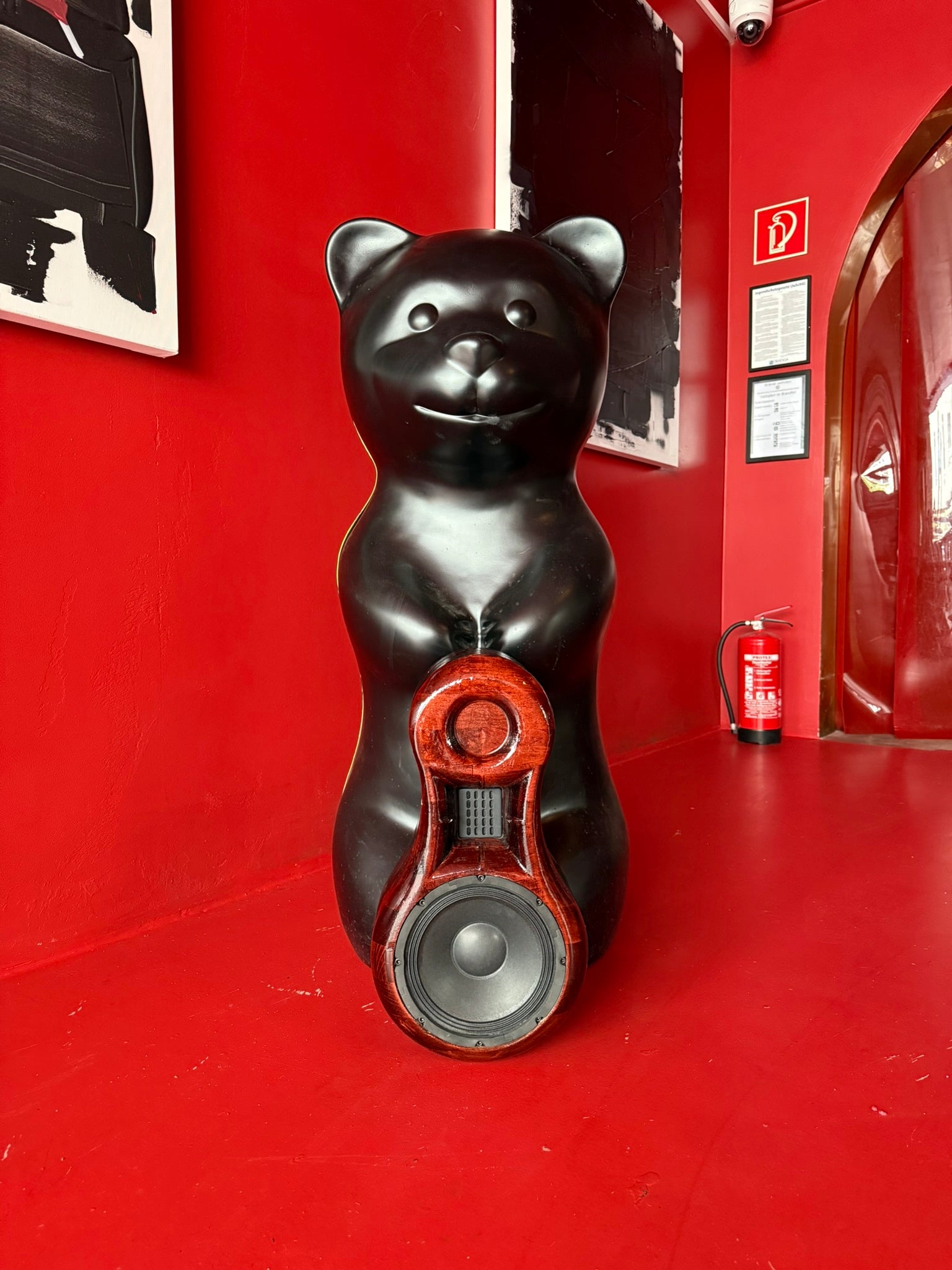 Black bear-shaped speaker on a red floor with a red wall in the background