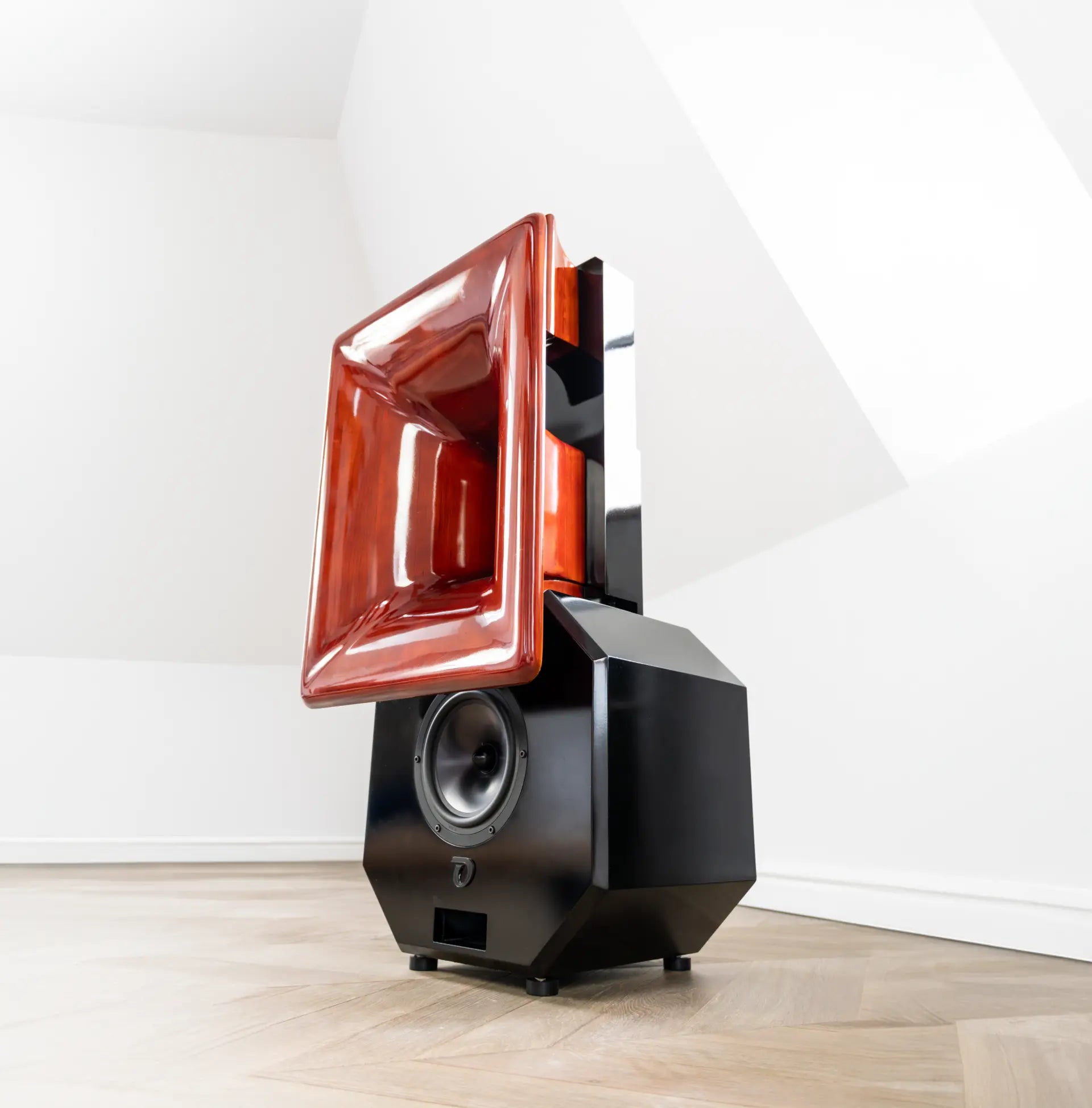 Modern speaker with a red front grille on a white wall background